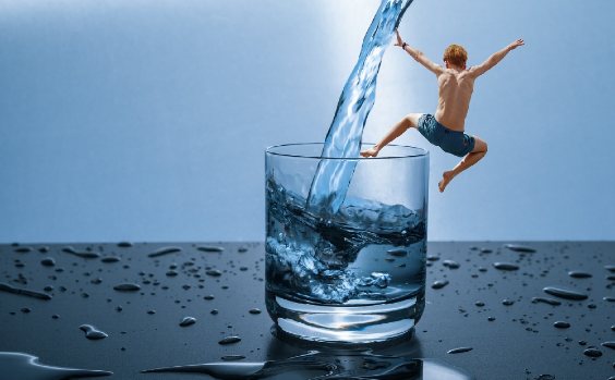 Bildkomposition: Junge springt in ein Wasserglas