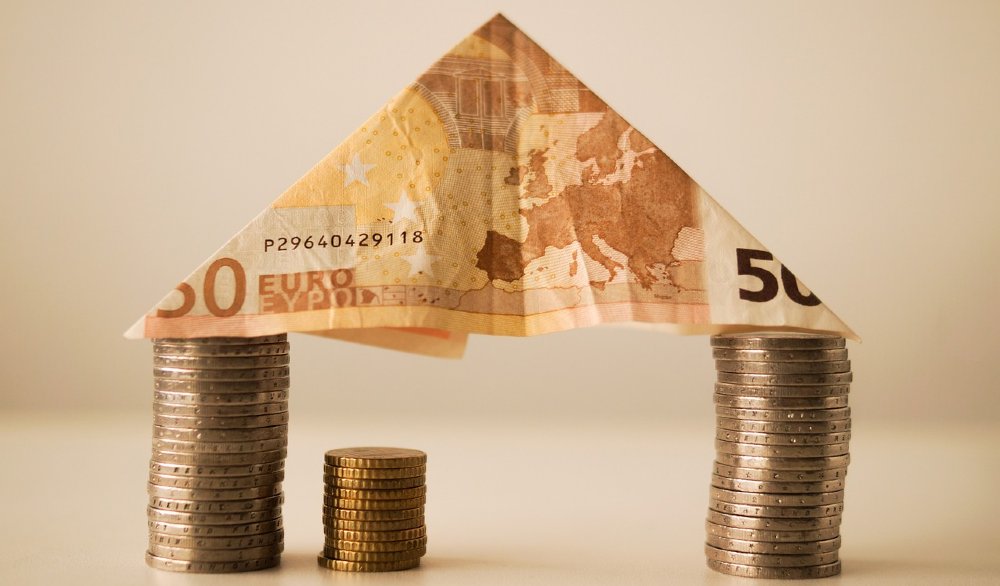 50-Euro-Schein als Dach auf Münzstapeln